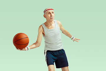 Image showing Senior man playing basketball in sportwear isolated on green background