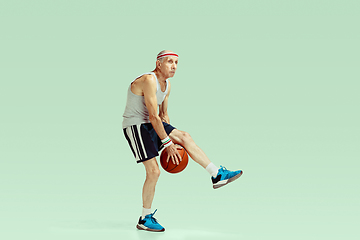 Image showing Senior man playing basketball in sportwear isolated on green background