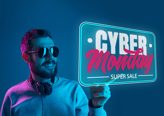 Image showing Half-length close up portrait of young man in neon light with cyber monday lettering