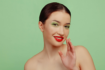 Image showing Portrait of beautiful young woman with bright make-up isolated on green studio background