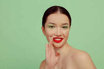 Image showing Portrait of beautiful young woman with bright make-up isolated on green studio background