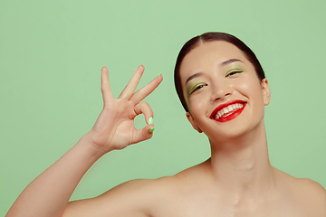 Image showing Portrait of beautiful young woman with bright make-up isolated on green studio background