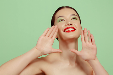 Image showing Portrait of beautiful young woman with bright make-up isolated on green studio background
