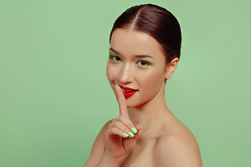 Image showing Portrait of beautiful young woman with bright make-up isolated on green studio background