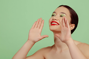 Image showing Portrait of beautiful young woman with bright make-up isolated on green studio background