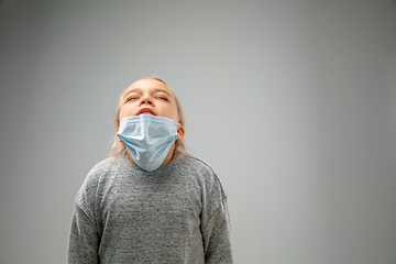 Image showing Caucasian girl wearing the respiratory protection mask against air pollution and dusk on grey studio background