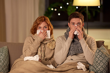 Image showing sick young couple with tissue blowing nose at home