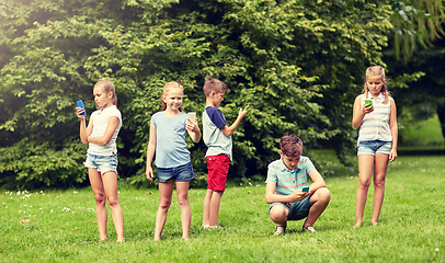 Image showing kids with smartphones playing game in summer park