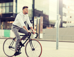 Image showing man with headphones riding bicycle on city street