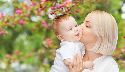 Image showing close up of happy mother kissing baby over garden