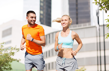 Image showing happy couple with fitness trackers running at city