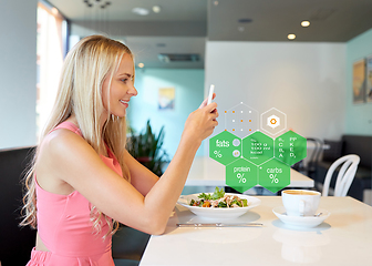 Image showing happy woman with smartphone eating at restaurant