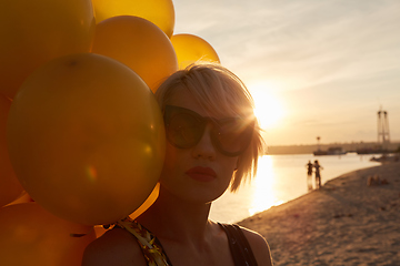 Image showing Young woman with many golden balloons.