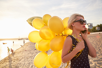 Image showing Young woman with many golden balloons.