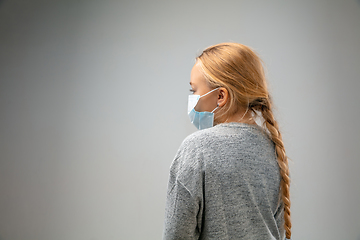 Image showing Caucasian girl wearing the respiratory protection mask against air pollution and dusk on grey studio background