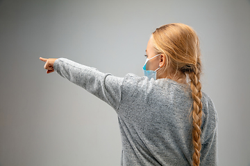 Image showing Caucasian girl wearing the respiratory protection mask against air pollution and dusk on grey studio background