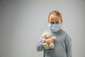 Image showing Caucasian girl wearing the respiratory protection mask against air pollution and dusk on grey studio background