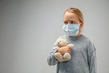 Image showing Caucasian girl wearing the respiratory protection mask against air pollution and dusk on grey studio background