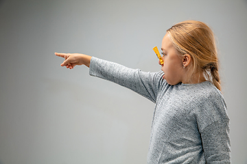 Image showing Caucasian girl wearing the respiratory protection pin clasp against air pollution and dusk on grey studio background