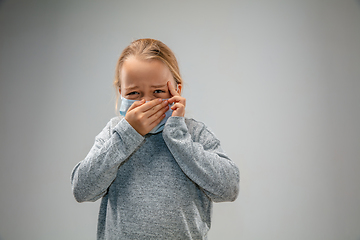 Image showing Caucasian girl wearing the respiratory protection mask against air pollution and dusk on grey studio background