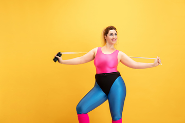 Image showing Young caucasian plus size female model\'s training on yellow background