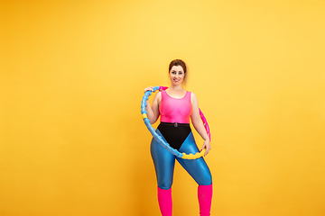 Image showing Young caucasian plus size female model\'s training on yellow background