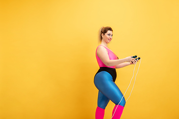 Image showing Young caucasian plus size female model\'s training on yellow background