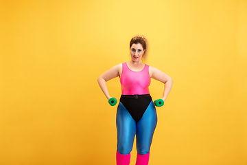 Image showing Young caucasian plus size female model\'s training on yellow background