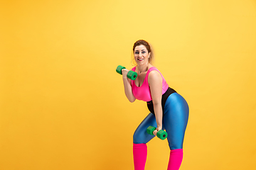 Image showing Young caucasian plus size female model\'s training on yellow background