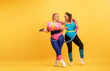 Image showing Young caucasian plus size female models training on yellow background