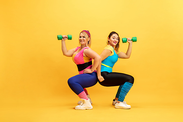 Image showing Young caucasian plus size female models training on yellow background