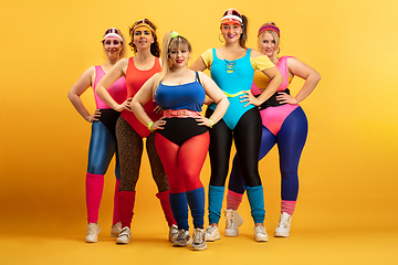 Image showing Young caucasian plus size female models training on yellow background