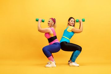 Image showing Young caucasian plus size female models training on yellow background