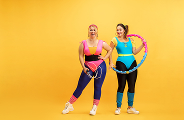 Image showing Young caucasian plus size female models training on yellow background