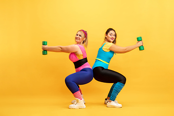 Image showing Young caucasian plus size female models training on yellow background