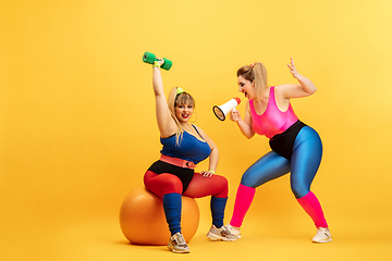 Image showing Young caucasian plus size female models training on yellow background