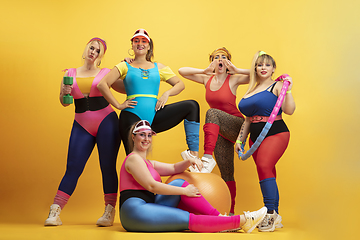 Image showing Young caucasian plus size female models training on yellow background