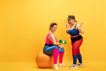 Image showing Young caucasian plus size female models training on yellow background