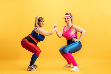 Image showing Young caucasian plus size female models training on yellow background