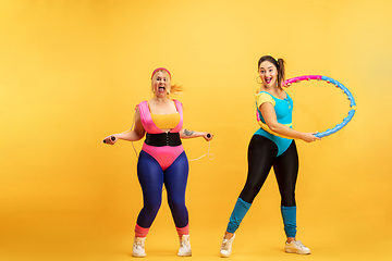 Image showing Young caucasian plus size female models training on yellow background