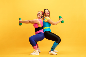 Image showing Young caucasian plus size female models training on yellow background