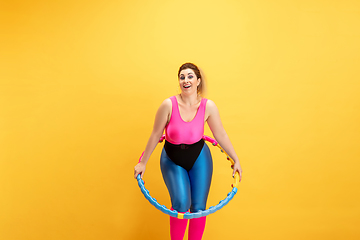 Image showing Young caucasian plus size female model\'s training on yellow background