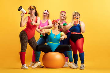 Image showing Young caucasian plus size female models training on yellow background