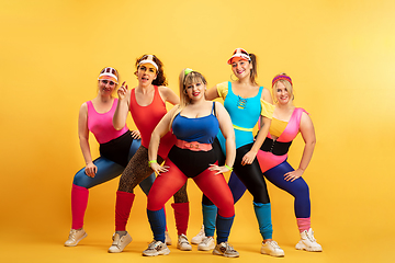 Image showing Young caucasian plus size female models training on yellow background