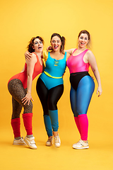 Image showing Young caucasian plus size female models training on yellow background