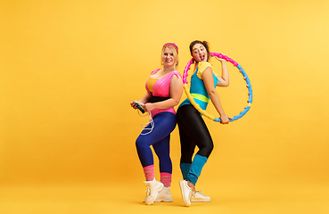 Image showing Young caucasian plus size female models training on yellow background