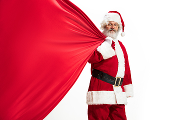 Image showing Santa Claus pulling huge bag full of christmas presents isolated on white background