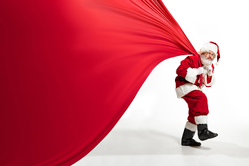 Image showing Santa Claus pulling huge bag full of christmas presents isolated on white background