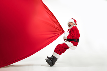 Image showing Santa Claus pulling huge bag full of christmas presents isolated on white background