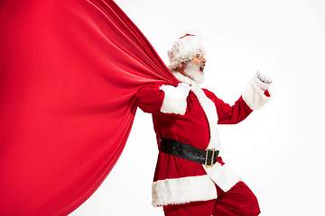 Image showing Santa Claus pulling huge bag full of christmas presents isolated on white background